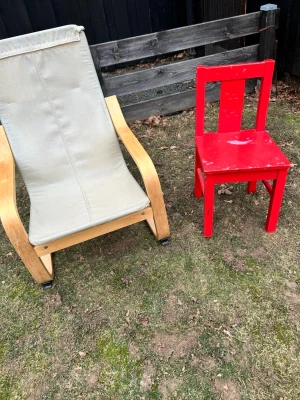 Röd barnstol och loungestol - Säljer en röd barnstol i trä och en loungestol med ljus tygsits och böjda träarmstöd. Barnstolen är helröd och har en klassisk design, medan loungestolen har en modern look med naturfärgat trä och ljus sits. Perfekt för både ute och inne.