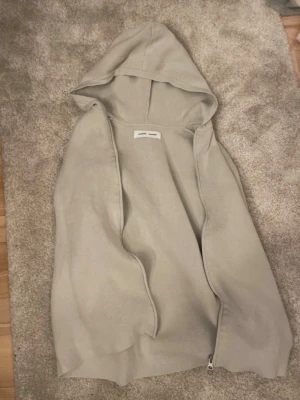 Beige hoodie med dragkedja Samsøe Samsøe - Ljusbeige hoodie från Samsøe Samsøe med dragkedja framtill och stor huva. Tillverkad i mjukt bomullsmaterial som känns skönt mot huden. Enkel och clean design utan tryck eller mönster, perfekt för en avslappnad look.
