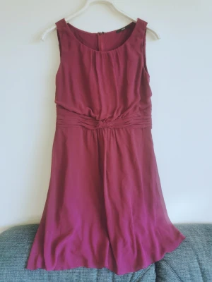 Cerise knälång ärmlös klänning - Cerise knälång fodrad ärmlös klänning i polyester/viskos. Gott skick, inga skador eller fläckar. 