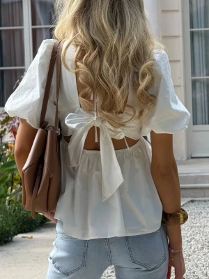 Vit blus med knyt i ryggen - Säljer sötaste blusen från Meet Me there, Filippas kollektion. Blusen har puffärmar och knyt i ryggen. Använd endast en gång och så fin! 🌷