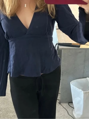 Mörkblå blus med rosett baktill  - Snygg mörkblå omlottopp med v-ringning och långa ärmar. Från Gina tricot. Pris kan diskuteras skriv om ni är intresserade