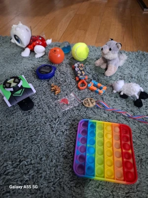 Blandat leksakspaket med pop it - Säljer ett blandat paket med leksaker: regnbågsfärgad pop it, mjukisdjur (varg och får), robotdjur, studsbollar, medalj, armband, nyckelringar och en leksaksbil. Perfekt för dig som gillar småprylar och gadgets.
