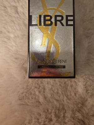 Yves Saint Laurent Libre L'Absolu Platine - Exklusiv parfym från Yves Saint Laurent, Libre L'Absolu Platine. Flaskan har en lyxig design i silver och guld med den ikoniska YSL-loggan. Perfekt för dig som vill ha en elegant och modern doft i din samling.