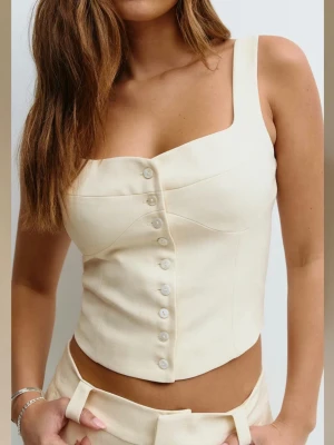 Beige korsettopp från Gina tricot med knappar - Trendig beige korsettopp med snygg knappdetalj framtill. Toppen har breda axelband, figurnära passform och markerad midja. Perfekt att styla med höga byxor eller kjol för en cool look.