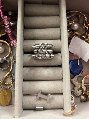 Silvrig ring med nitar - Cool ring i silverfärgad metall med flera små, pyramidformade nitar på ovansidan. Ringen har en bred design och ger ett edgy intryck, perfekt för dig som gillar statement-smycken.