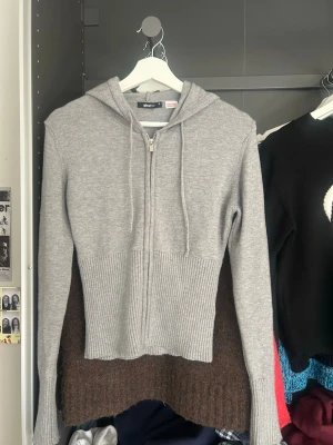 Grå stickad zip up hoodie från Gina - Säljer en unik hoodie från Gina i grått. Den har dragkedja framtill, ribbstickade detaljer och en huva. Materialet är mjukt och stickat, perfekt för dig som gillar en avslappnad men ändå stilren look. Storlek M men passar S oxå.