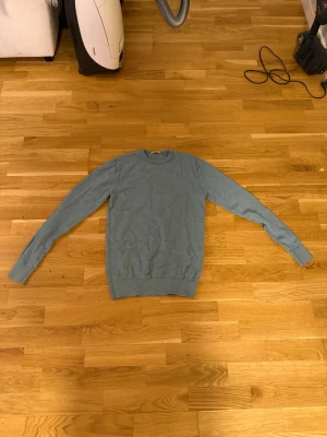 Blå rundhalsad tröja - En stilren blå tröja med rund halsringning och långa ärmar. Tröjan har en enkel design utan tryck eller mönster och är tillverkad i ett mjukt, tunt material som passar perfekt till lager-på-lager-stil. Är storlek S men sitter som XS från John Henric