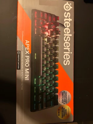 SteelSeries Apex Pro Mini tangentbord (oöppnad) - SteelSeries Apex Pro Mini är ett kompakt gamingtangentbord med RGB-belysning och OmniPoint-switchar. Tangentbordet har en svart design och är optimerat för turneringsspel med 60% formfaktor. Perfekt för dig som vill ha snabb respons och snygg belysning HELT OÖPPNAD .