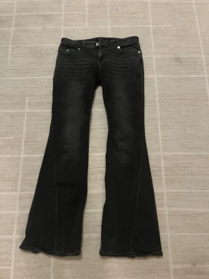 Svarta/gråa jeans True Religion - Svarta/gråa bootcut jeans från True Religon i strl W27. Köpta från Nelly. Jeansen är tyvärr för stora för mig. Jeansen har jag använt fåtal gånger💗