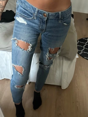 Blå low waisted jeans - Blåa low waisted jeans med revor Superstretchiga och sköna att ha på sig. Är i använt men i gott skick Dessa är i strl 4, vilket motsvarar ungefär strl S