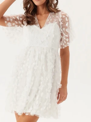 Vit blommig studentklänning med spets - Supersöt vit studentklänning med transparenta ärmar och blommigt spetsmönster. Helt ny med prislappen kvar. Nypris 999 kr