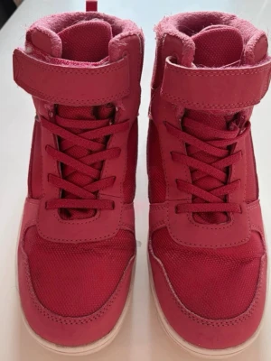 Rosa high top sneakers med kardborre - Snygga rosa high top sneakers med kardborreband och snörning. Skorna har en cool streetstil med ovandel i textil och syntetmaterial. Perfekta för dig som vill sticka ut med färg och komfort. Storlek 38