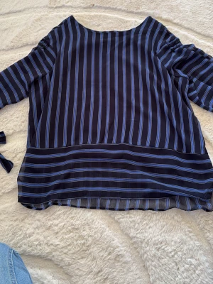 Randig blus från Mango i blått - Snygg blus från Mango med vertikala och horisontella ränder i blått och svart. Blusen har lång ärm och är tillverkad i ett lätt, transparent material som ger en luftig känsla. Perfekt att styla med jeans eller kjol för en trendig look.