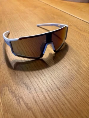 Pitwipers - Säljer ett par sportiga solglasögon med vit båge och stora spegelglas i futuristisk design. Perfekta för dig som vill sticka ut och få en cool look till sommaren. Sitter bekvämt och skyddar bra mot solen.