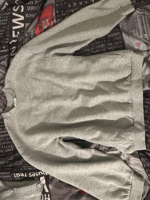 Grå basic sweatshirt - En enkel och stilren grå sweatshirt med rund hals och ribbade muddar vid ärmslut och nederkant. Perfekt för en avslappnad och casual look. Tillverkad i mjukt material som känns skönt mot huden.