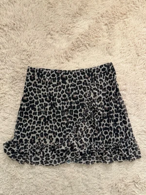 Kortkjol med volang - Säljer en snygg kortkjol med leopardmönster och volangkant. Kjolen har omlott-look framtill och är i storlek 158/164. Eftersom det är barnstorlek kan jag ej använda den som en kjol, därför använder jag den som en topp och passar helt perfekt då på mig som vanligen brukar ha storlek XS/S.💕💕😇