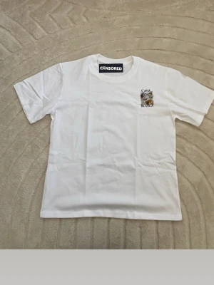 Vit Casa Blanca t-shirt med tryck - Vit t-shirt från Casa Blanca med färgglatt konstnärligt tryck på ryggen och mindre tryck på bröstet. Klassisk passform och rund halsringning. Perfekt för dig som gillar streetwear och vill sticka ut med snygg grafik.