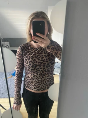 Leopardmönstrad långärmad topp - Säljer en snygg långärmad topp med leopardmönster. Toppen har en tight passform och är tillverkad i ett stretchigt material som sitter skönt på kroppen. 
