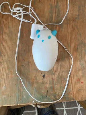 Söt nattlampa katt med USB-sladd - En vit nattlampa i silikon formad som en katt med blå öron och detaljer. Lampan har USB-sladd för laddning och är kompakt och smidig att ha på nattduksbordet. Perfekt som mysbelysning i sovrummet eller barnrummet.