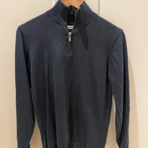 Mörkblå tröja med dragkedja från MNG - Snygg mörkblå tröja från MNG med halv dragkedja och ribbad krage. Perfekt för en stilren look. Tröjan har långa ärmar och är tillverkad i ett mjukt material som ger en bekväm passform.