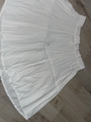 Vit kjol från Bik Bok i bomull - Säljer en vit kjol från Bik Bok i storlek XS. Kjolen är gjord i ett tunt och luftigt bomullstyg med resår i midjan för skön passform. Perfekt till sommaren och enkel att matcha med olika toppar.