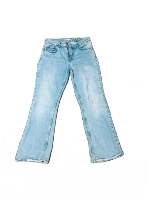 Ljusblå bootcut jeans - Säljer ett par ljusblå bootcut jeans med klassisk femficksdesign och utsvängda ben. Jeansen har en avslappnad passform och är tillverkade i denim. Perfekta för en trendig och avslappnad stil.