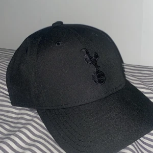  Tottenham keps från New Era - Snygg svart keps från New Era med Tottenham Hotspur-logga broderad framtill i svart. Använd ett fåtal gånger så 10/10 skick och köpt från Tottenhams officiella hemsida.✅