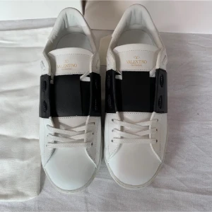Valentino Garavani vita sneakers - Snygga vita sneakers från Valentino Garavani med en bred svart läderdetalj över mitten. dom är äkta har kvitto 