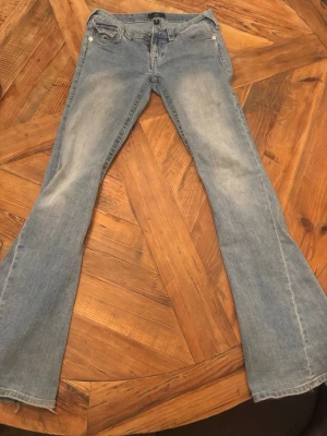 Ljusblå bootcut jeans True Religion - Säljer mina true religon jeans då dom börjar bli lite små, Dom har endast lite slitningar nere vid byxändan och en mascara fläck på ena låret men inget man tänker på! Väl använda men i bra skick