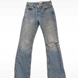 Ljusblå bootcut jeans med slitning - Säljer ett par ljusblå bootcut jeans med slitning och hål på höger knä. 