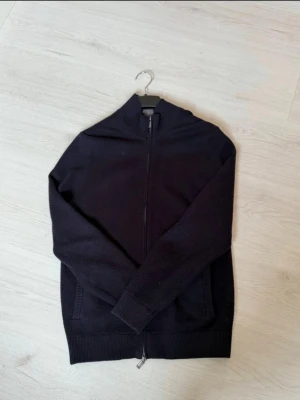 Svart ziptröja från Massimo Dutti - Stilren Marinblå ziptröja från Massimo Dutti med hög krage och ribbade muddar. Tröjan har hel dragkedja framtill och är tillverkad i ett mjukt material som passar perfekt till lager-på-lager. Använd få gånger! 