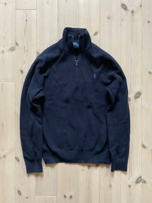 Stickad tröja från Ralph Lauren - Stickad tröja från Polo Ralph Lauren med halv dragkedja och hög krage.                                         Strechigt material och i bra skick. Inga defekter. 
