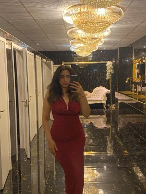 Vinröd långklänning med v-ringning - Elegant vinröd långklänning med v-ringad hals och figurnära passform. Klänningen har ärmlös design och markerad midja, vilket ger en smickrande siluett. Har även öppen rygg och fler bilder kan skickas! Använts endast en gång på en förlovning!