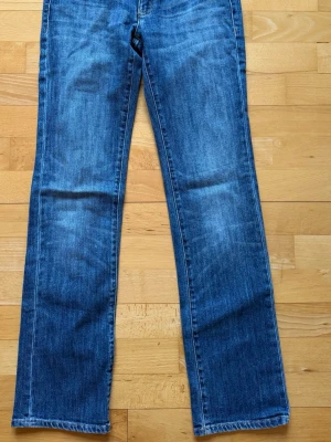Armani Blå raka jeans med klassisk tvätt - Säljer ett par blå jeans med rak passform och klassisk tvätt. Jeansen har fem fickor, normal midja och subtila slitningar för en avslappnad look. Perfekta till vardagsstilen och passar till det mesta. Materialet är mjukt denim i bomull.