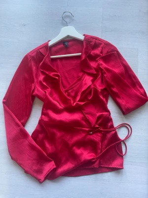 Röd omlottblus från H&M - Snygg röd omlottblus från H&M. Lite tajt vid armarna tyckte jag men annars jätte fin. S/M