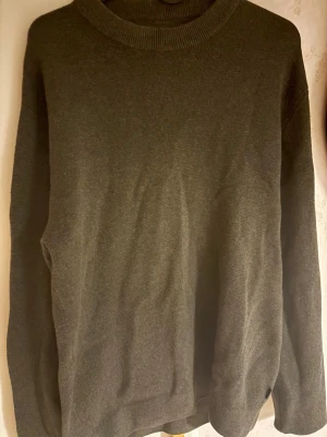 Mörkgrå stickad tröja Jack & Jones - Mörkgrå stickad tröja från Jack & Jones med rund halsringning och ribbade muddar. Enkel och stilren design som passar perfekt till lager-på-lager. Materialet känns mjukt och bekvämt mot huden.