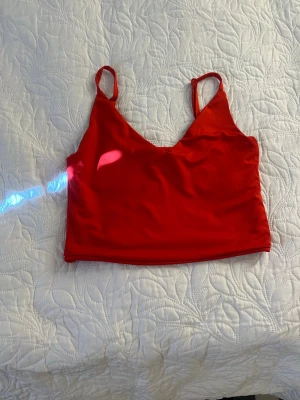 Röd croppad linnetopp - Snygg röd croppad linnetopp med smala axelband och v-ringad hals. Perfekt till sommaren och enkel att matcha med jeans eller kjol. Tunn och lätt, passar bra för varma dagar.