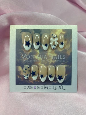 MidnightStar (S);Medium Almond - Snygga handgjorda press-on naglar i en medium almondform. Naglarna har en nude bas, vit fransk tipp och dekoreras med mörkblå stjärnor samt en söt 3D-rosett på en nagel. Perfekt för dig som vill ha en unik och trendig look.S: 15 mm, 11,5 mm, 12 mm, 11 mm, 9 mm 