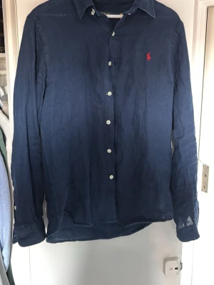 Marinblå linneskjorta från Polo Ralph Lauren - Köpt förra sommaren använd 3 gånger. Hör av er vid frågor