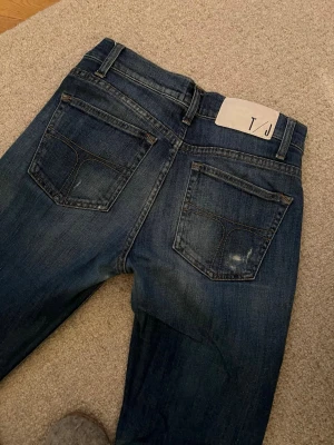 Mörkblå skinny jeans från tiger Jeans - Säljer ett par mörkblå skinny jeans från Tiger Jeans med råa, avklippta benslut och klassiska bakfickor. Jeansen har en snygg tvätt med lätt slitna original detaljer och är tillverkade i Japansk denimtyg för skön passform och hög kvalitet. 