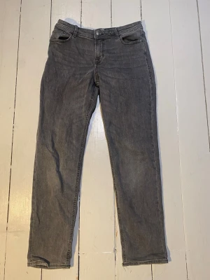 Grå jeans från Jack & Jones 170cm/ 15Y - Snygga grå jeans från Jack & Jones med rak passform och klassisk femficksdesign. Jeansen har bälteshällor, knappgylf och är tillverkade i ett mjukt denimtyg som ger en avslappnad look. Perfekta för dig som gillar en enkel och stilren stil.