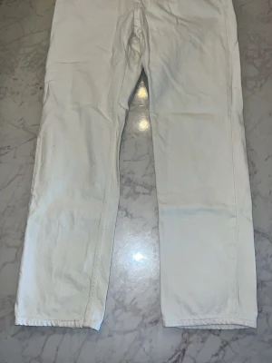 Vita raka jeans från Zara - Säljer ett par vita jeans med rak passform och klassisk femficksdesign. Jeansen har normal midja och är tillverkade i ett kraftigare denimtyg. Perfekta för dig som vill ha en clean och stilren look.