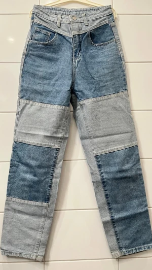 Patchwork jeans i två nyanser denim - Unika patchwork jeans i två olika blå denimnyanser. Rak passform med hög midja och klassiska fem fickor. Snygg kontrast mellan ljus och mörk denim framtill och baktill. Tillverkade i bomull för en skön och slitstark känsla. Perfekta för dig som vill sticka ut!