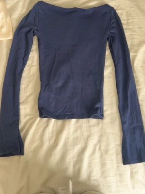 Mörkblå långärmad topp Gina Tricot - En enkel och stilren mörkblå långärmad topp från Gina Tricot. Toppen har en tight passform och är tillverkad i mjukt material som sitter skönt mot kroppen. Perfekt att matcha med jeans eller kjol för en clean look.