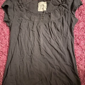 Fin grå topp med knappar - Så fin t-shirt/ blus som är köpt på plick och använd fåtal gånger. Väldigt bra skick och passar xs/s! 💓Pris går att diskutera så bara skriv!!