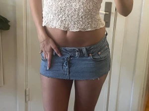  minikjol - Supersnygg blå jeans minikjol med klassiska fickor och knappdetaljer framtill. Kjolen har en riktigt kort passform och rå kant nedtill för en trendig look. Perfekt för dig som vill sticka ut och köra på en edgy stil.