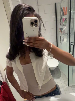 Vit kortärmad blus med knappar - Säljer en vit kortärmad blus med knappar framtill. Blusen har en klassisk krage och är lätt croppad, vilket ger en trendig look. Perfekt att styla över ett linne eller topp. Enkel och stilren design som passar till många outfits🌸