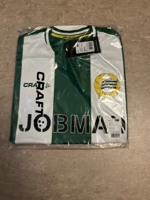 Hammarby matchtröja Craft grön/vit - Äkta Hammarby matchtröja från Craft i grönt och vitt med klassiska vertikala ränder. Tröjan har klubbmärke på bröstet, JOBMAN-tryck och rund hals. Tillverkad i lätt och funktionellt material som passar perfekt till fotbollsträning eller match.
