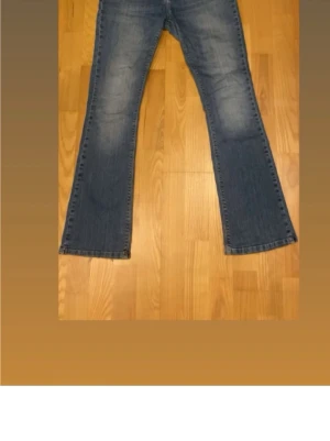 Bootcut jeans  - Snygga blå lågmidjade bootcut jeans med ljusa slitningar och en broderad lilja på myntfickan. Jeansen är från Morris, deras damkollektion. Storlek 30/32💞
