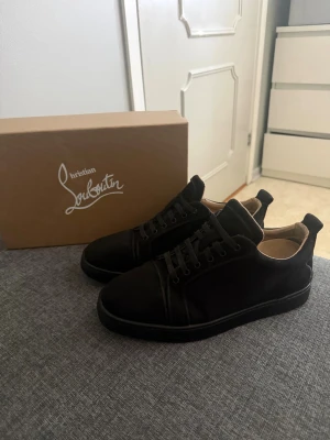 Svarta sneakers från Christian Louboutin - Snygga svarta sneakers från Christian Louboutin i mocka med klassisk låg profil och svarta snören. Skorna har en stilren design med diskreta sömmar och beige innerfoder. Perfekta för dig som vill ha en exklusiv och clean look. Jätte fin mocka använda i 1 vecka sitter fint väldigt bra om behandlade BUD SOM GÄLLER!! Köpta i Köpenhamn kvitto med följer så klart och jag skickar bild på kvittot med mitt namn på undertill